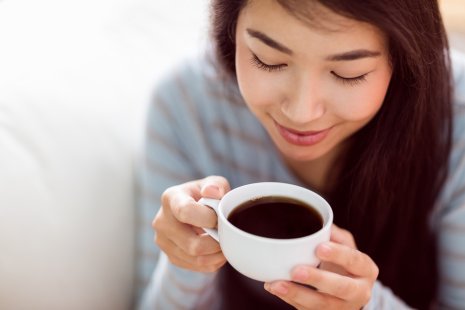 Naisen kädessä valkoinen kahvikuppi täynnä kahvia