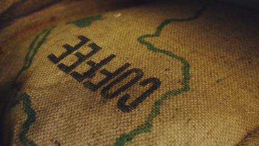 Kahvin kuljetukseen tarkoitettu juuttisäkki, jossa lukee coffee.